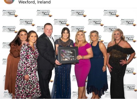 The Saints team at the Hair, Beauty and Style Awards photo wall with their framed winner’s certificate.