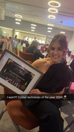 Louisa Murphy at the awards table holding her framed Best Colour Technician 2024 certificate.